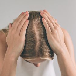 Women's hair is a top view close-up. Blonde woman is wearing shirt isolated on white