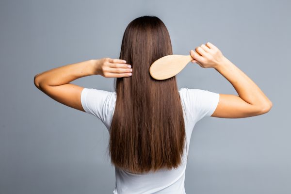 rear-view-of-combing-healthy-long-straight-female-hair-isolated-on-gray rear-view-of-combing-healthy-long-straight-female-hair-isolated-on-gray